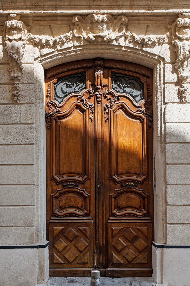 Architecturally magnificent carved wood doors and stone facade of a building near Avignon Hôtel Particulier, a beautifully restored 19th century mansion in the heart of Avignon’s historic center - Haven In. #frencharchitecture #oldworldstyle #carveddoors #frenchchateau #provence #frenchcountry #southoffrance