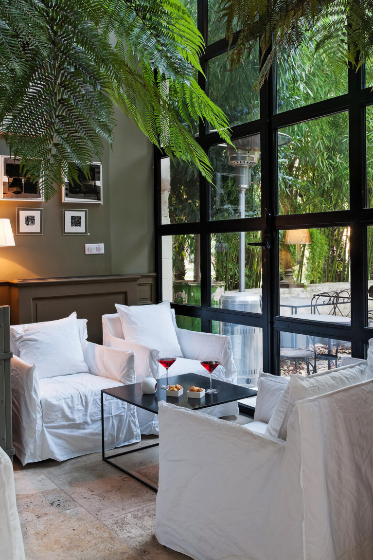Modern French style lounge with deep taupe walls and white slipcovered chairs in the exquisite Avignon Hôtel Particulier, a beautifully restored 19th century mansion in the heart of Avignon’s historic center - Haven In. #frenchchateau #provence #frenchcountry #restoredchateau #southoffrance #aivgnon