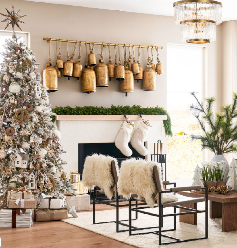 Gold Christmas bells suspended from track over a fireplace with greenery and candles - Pottery Barn. #christmasbells #goldbells #christmasdecor