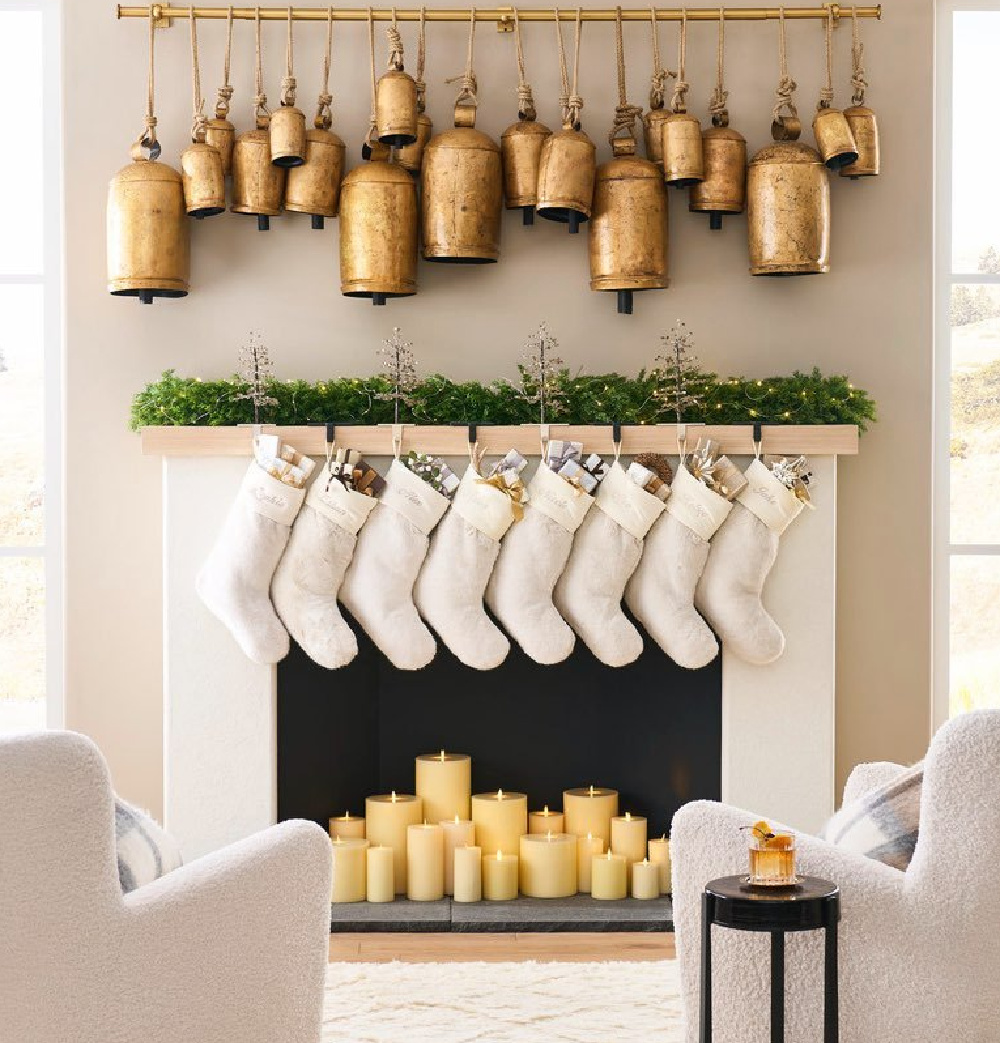 Gold Christmas bells suspended from track over a fireplace with greenery and candles - Pottery Barn. #christmasbells #goldbells #christmasdecor