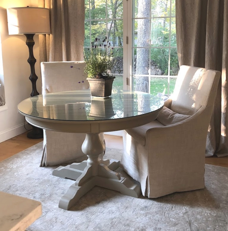 Serene Decor in our breakfast nook with Belgian linen slipcovered chairs, round dining table, and Couristan area rug - Hello Lovely Studio. #hellolovelystudio #breakfastnook #belgianlinen #slipcoveredchairs #cozykitchen #europeancountry #frenchcountrystyle