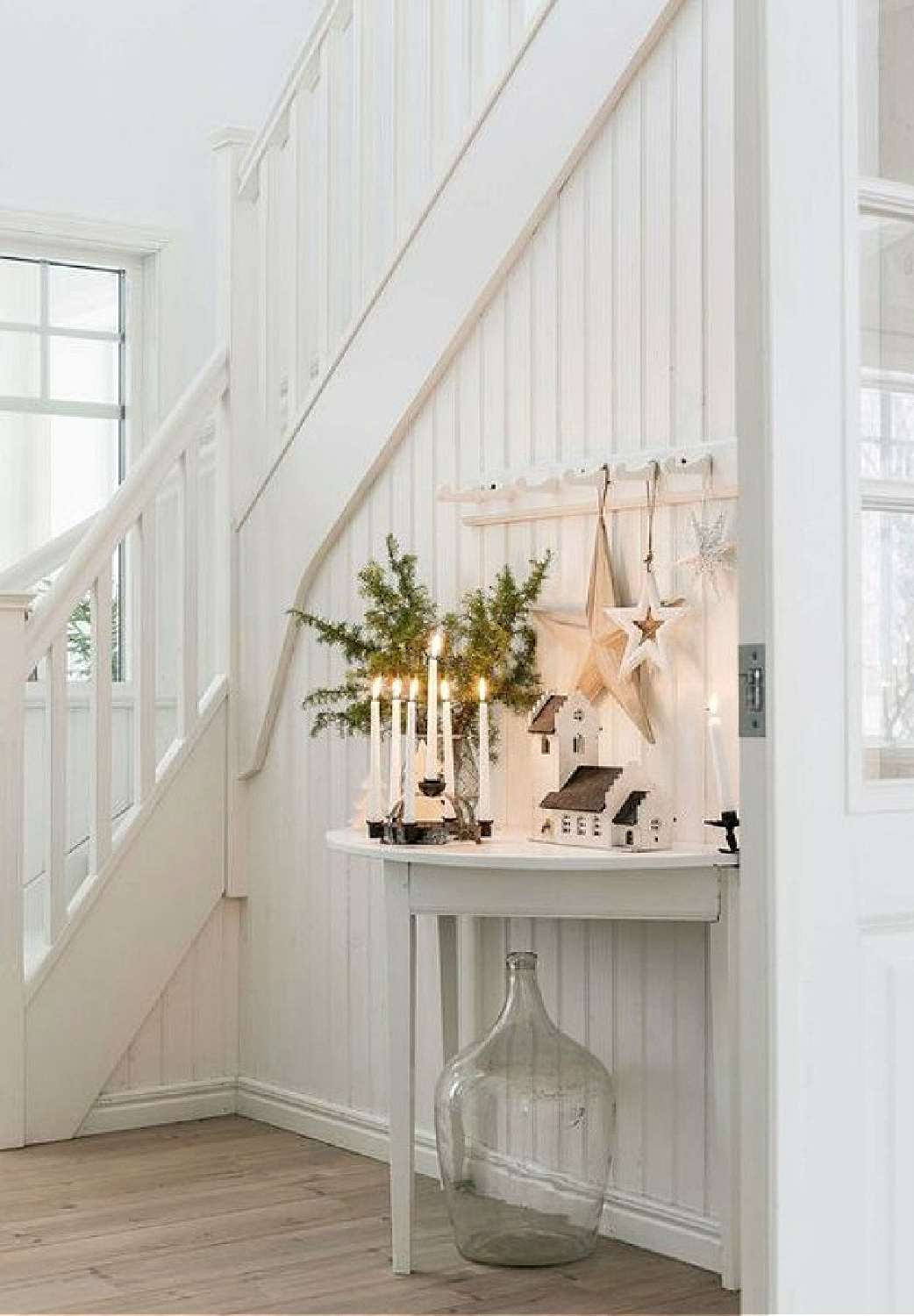 Gorgeous Scandinavian white Christmas decorating in a white cottage style entry with candlelight - Lantliv. #whitechristmasdecor #scandichristmas