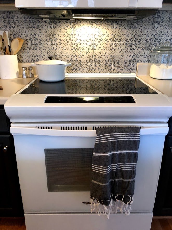 Modern white Whirlpool smooth top electric range in a kitchen with Spanish tile backsplash.