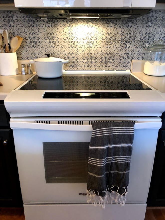 Modern white Whirlpool smooth top electric range in a kitchen with Spanish tile backsplash.