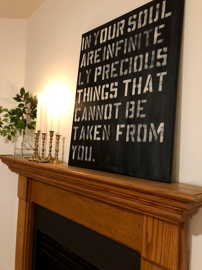 Oak fireplace surround with brass candlesticks, a simple branch, and artwork from Hello Lovely Studio with quote from Oscar Wilde.