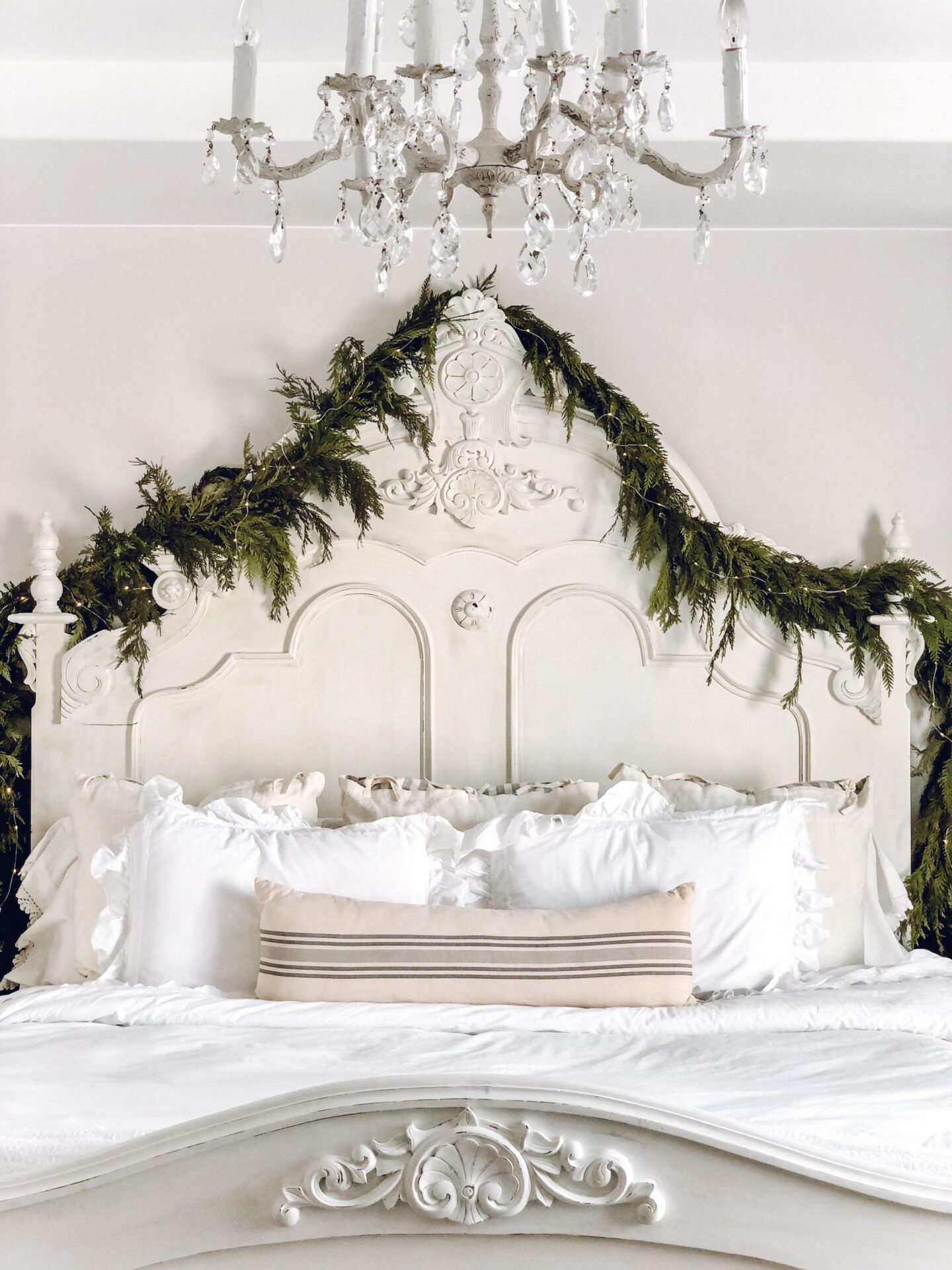 Charming country cottage white bedroom with antique headboard decorated simply with fresh greenery - Le Cultivateur. #holidaydecor #christmasgarland #bedrooms 