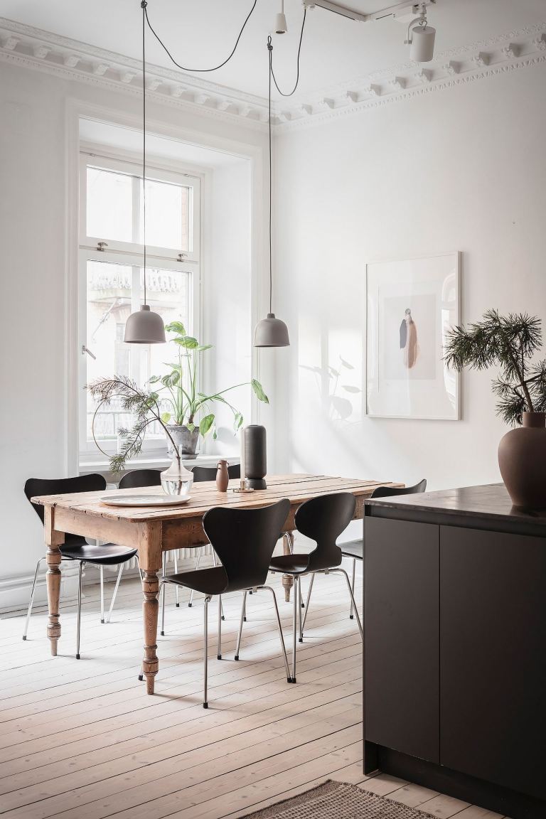 Zen dining room with white walls, modern black chairs, and natural wood farm table exuding Scandinavian style - PlaneteDeco.