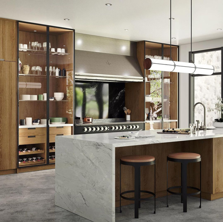 Modern French kitchen with wood custom cabinets flanking French range and waterfall style island with counter stools - L'Atelier Paris. #modernfrench #luxurykitchen #bespoke #frenchrange