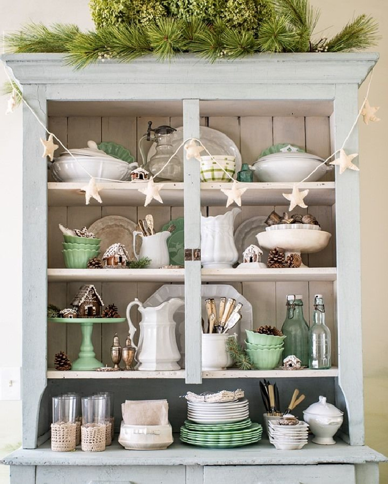 Christmas decor in a charming light blue country cupboard with open shelves and vintage dishware including jadeite - Miss Mustard Seed.