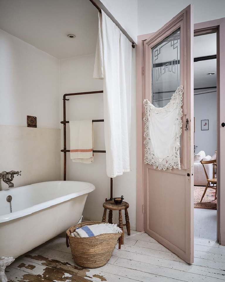 Serene rustic vintage zen bathroom with clawfoot tub, pink door, and white floors - design by Clare Lattin and appearing in HOME FOR THE SOUL by Sara Bird & Dan Duchars (Ryland Peters Small, 2020).