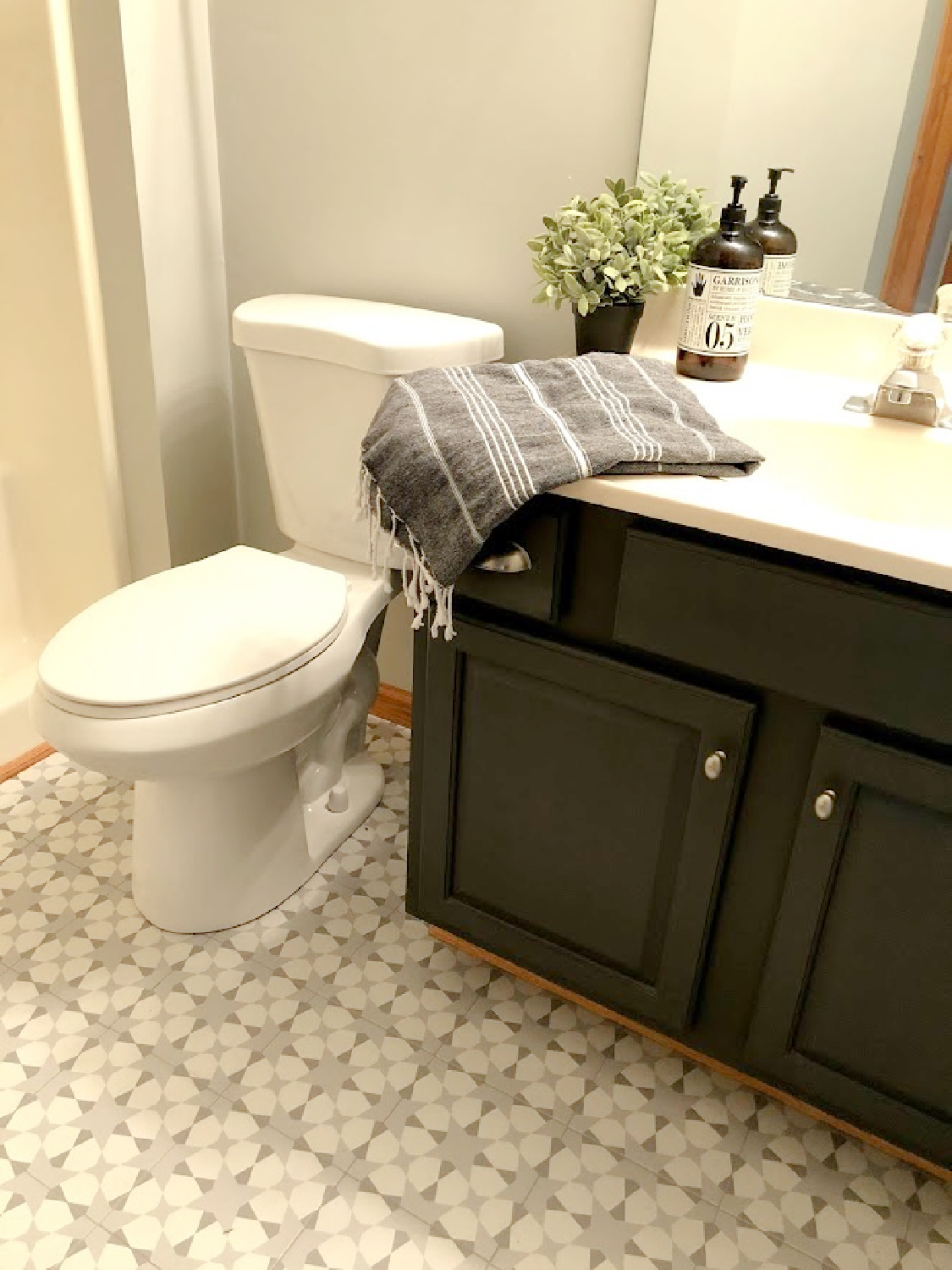 Sherwin Williams Carbonized paint color on a traditional vanity in a renovated bathroom - Hello Lovely Studio. #sherwinwilliams #carbonized #charcoalgrey #paintccolors