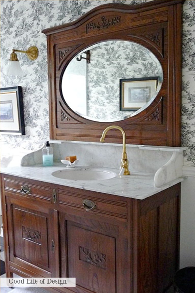 Antique style bathroom vanity in a traditional style bathroom with blue toile wallpaper - Good Life of Design. #grandmillennial #interiordesign #bathroom