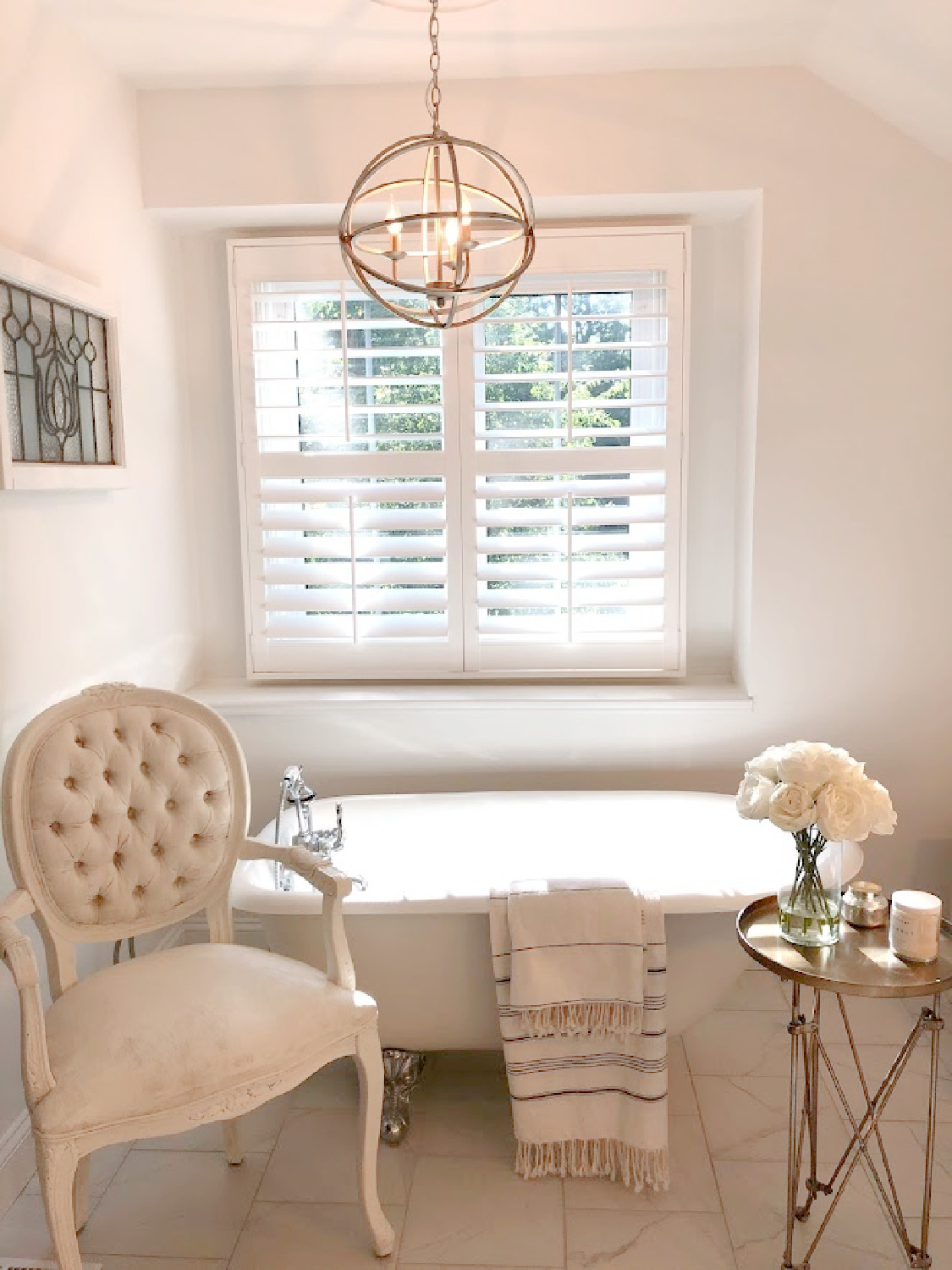 My modern French white bathroom with clawfoot tub, Louis chair, Turkish towels, and campaign table - Hello Lovely Studio. #modernfrench #bathroom