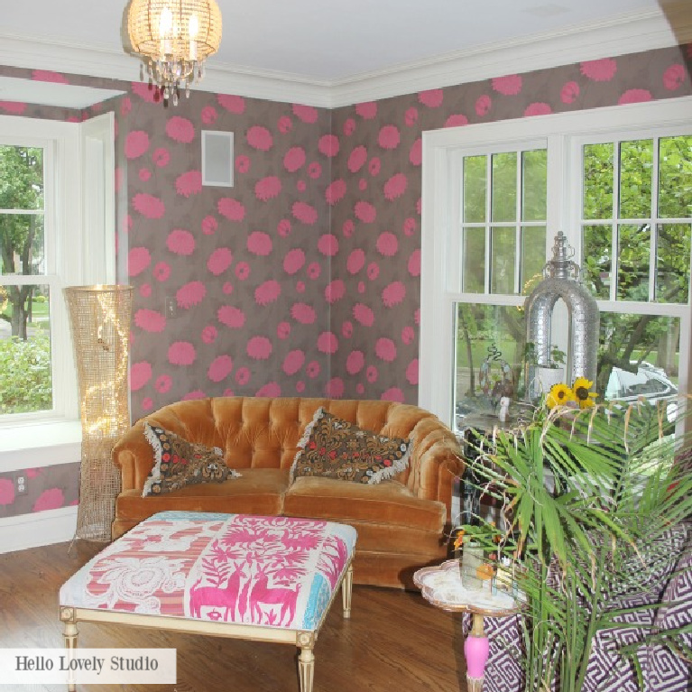 Boldly patterned wallpaper with hot pink in a den with orange velvet tufted settee reflects Grandmillennial style - Jenny Sweeney design on Hello Lovely.