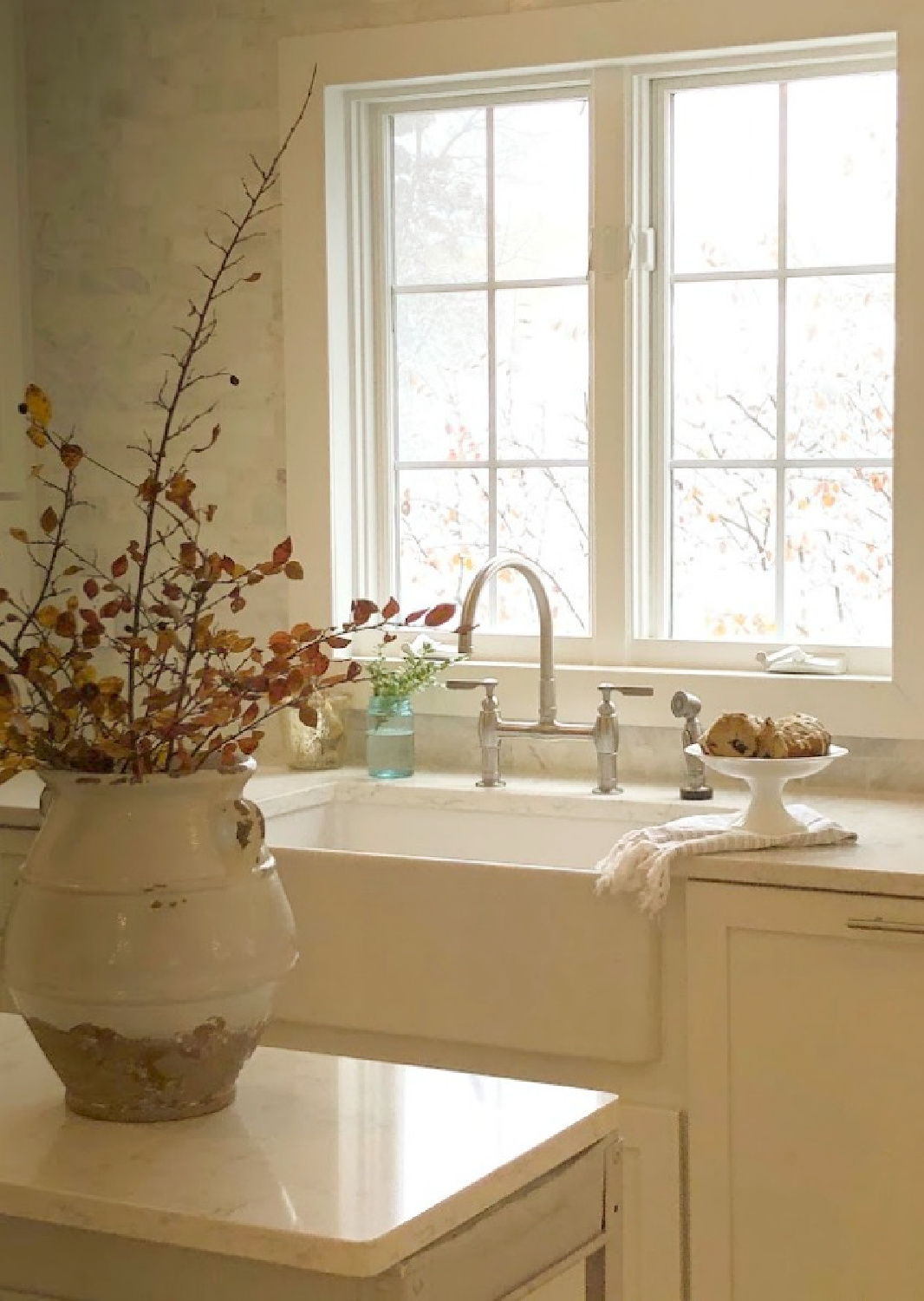 Warm white kitchen with industrial steel cart, farm sink, and Minuet (Viatera) white quartz counters - Hello Lovely Studio.