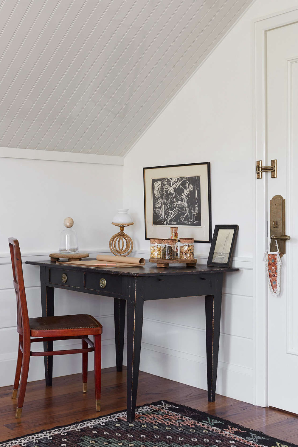 Guests can admire jars of beach finds and fill journals with travel notes at an unpretentious desk in weathered dark paint and a red-stained chairâthe kind of gentle mismatch that seafarers would have created out of heirlooms and purchases.