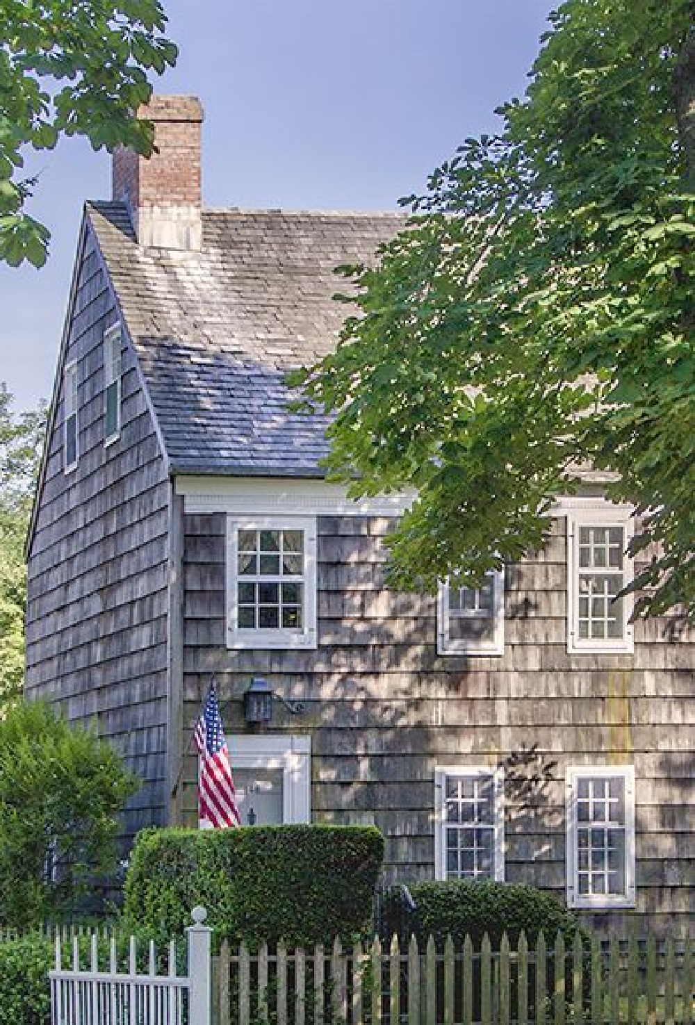 Main Street, East Hampton. A New England house exterior with American flag. COME TOUR MORE Nantucket Style Chic & Summer Vibes! #nantucket #interiordesign #designinspiration #summerliving #coastalstyle
