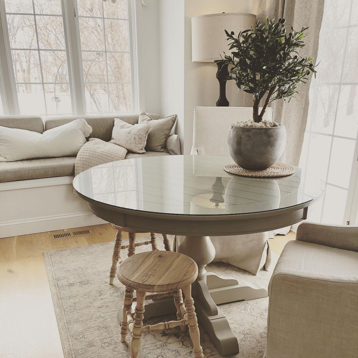 Serene and neutral European country inspired breakfast nook with window seat, round dining table, and Belgian slope arm chairs - Hello Lovely Studio.