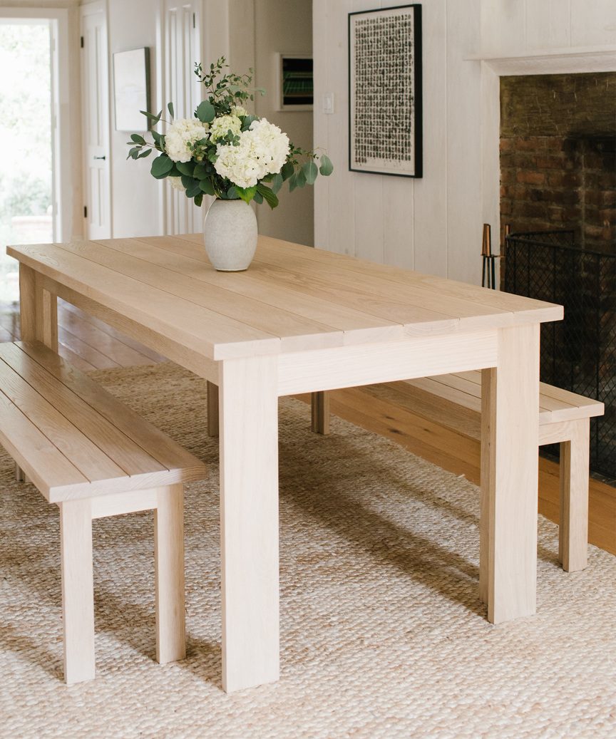 Jenni Kayne dining table and benches on jute rug with minimal design and clean lines.