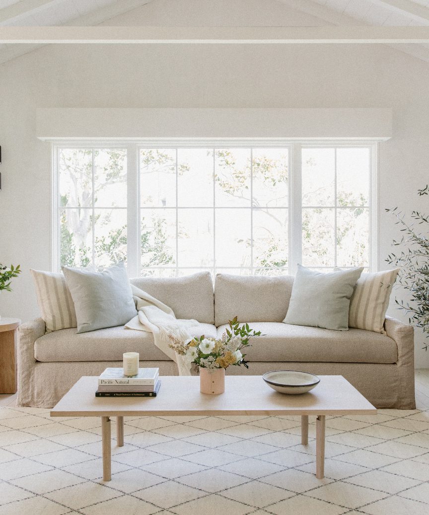 This Jenni Kayne Harbor Linen Sofa has a natural and luxurious look in this sunny living room with coffee table.