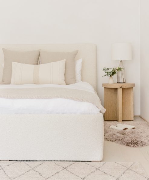 Natural, quiet, subdued mood in a lovely Jenni Kayne bedroom with rustic wood side table,white bedding and linens.