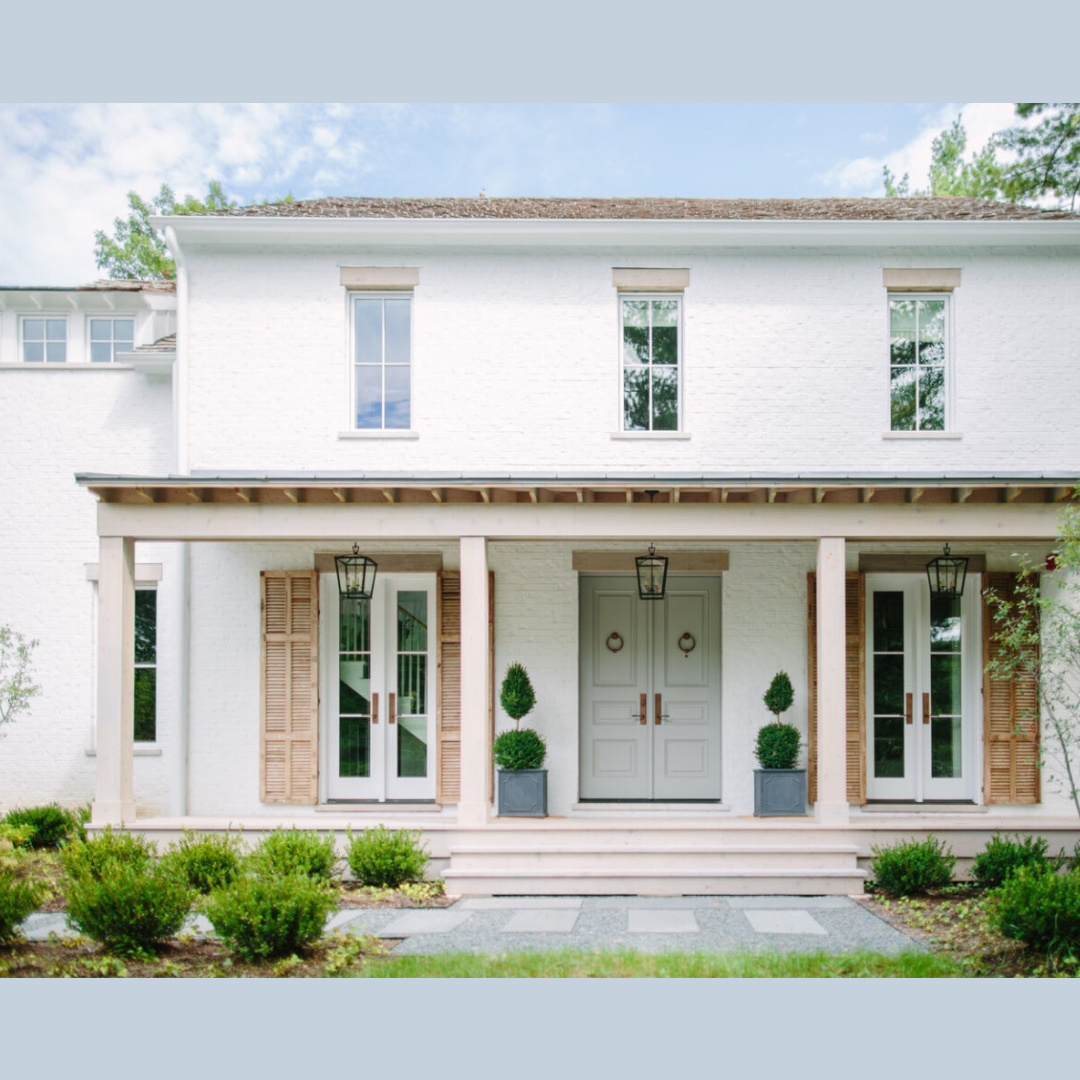 Gorgeous white brick house exterior with natural wood shutters and light blue grey door - Kate Marker Interiors (Grey Oak project in Barrington, IL).