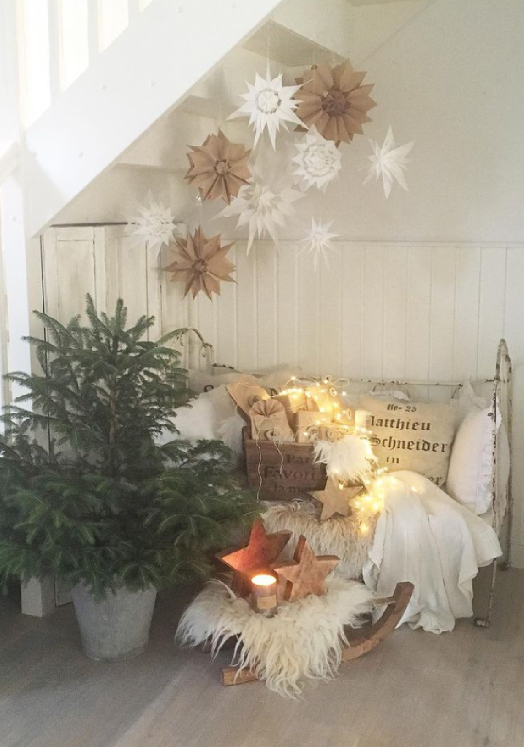 Scandi Christmas decor with paper snowflakes and a cozy settee in a beautiful cottage in Switzerland - Villa Jenal. #frenchnordic #nordicchristmas #scandiholidaydecor