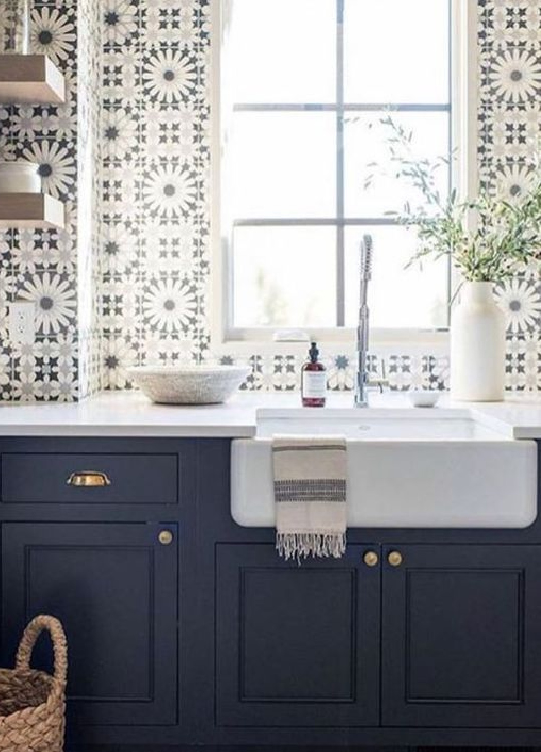 Stunning blue and white graphic tiles on sink wall of a country kitchen with navy blue cabinets and farm sink. 