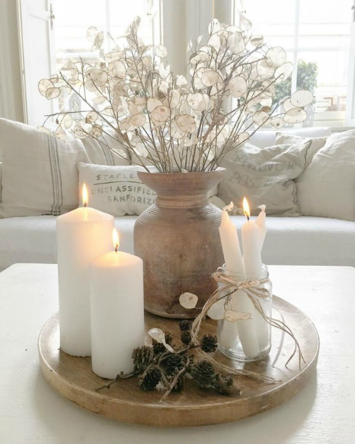 Serene and spare all white Scandi style living room with Mora clock and vignette with Lunaria on tray with candles - Villa Jenal. #frenchnordicstyle #nordicfrench #livingroom #swedishdecor #moraclock #interiordesign