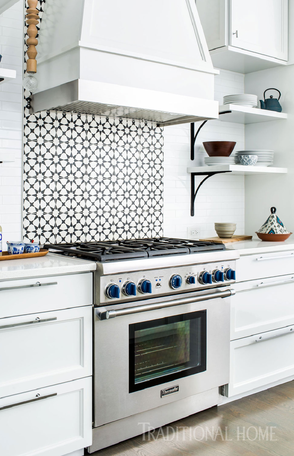 The custom vent hood above the Thermador range is mostly wood with a band of stainless steel closest to the heat. The patterned concrete backsplash tiles have color that goes all the way through. Come see 36 Best Beautiful Blue and White Kitchens to Love! #blueandwhite #bluekitchen #kitchendesign #kitchendecor #decorinspiration #beautifulkitchen