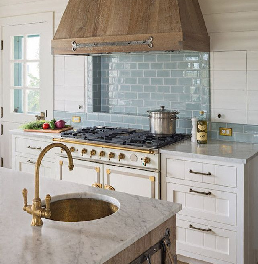 Turquoise blue subway tile behind range in gorgeous kitchen with rustic range hood. 
