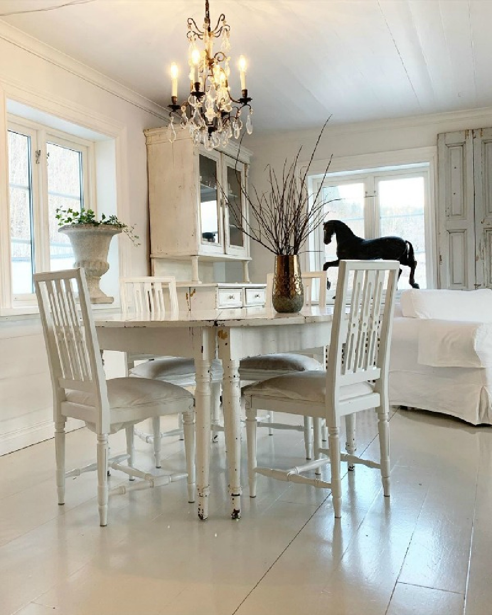 Charming all white dining room with white painted floors and French Nordic decor by Cathrine Aust. #frenchnordic #diningroom #allwhitedecor #scandinaviandesign