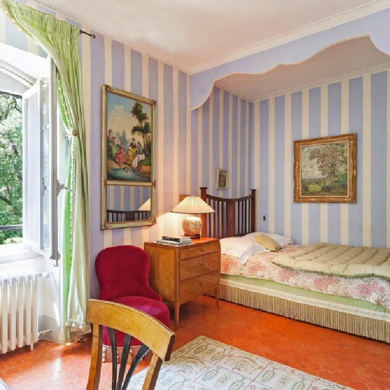 Elegant French country bedroom in a Provence chateau is decorated with stripe wallpaper, a nook for the bed, and desk area - Haven In.