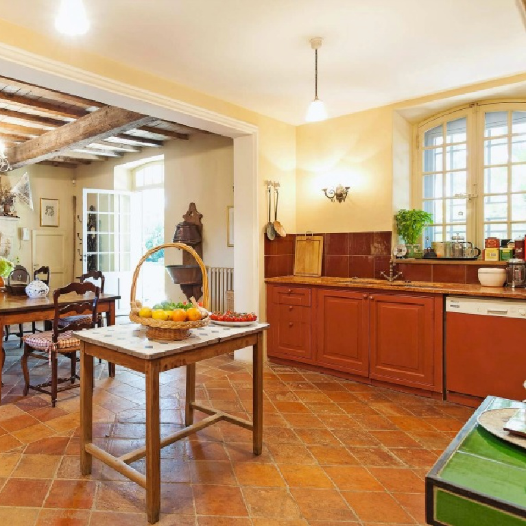 Cheerful and traditional with terracotta, green, and bright blue accents, this Provence kitchen with work table boasts timeless charm - Haven In. #frenchcountry #kitchens
