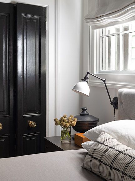 Understated and classic bedroom with glossy black closet doors in a room with design by Brian Paquette.