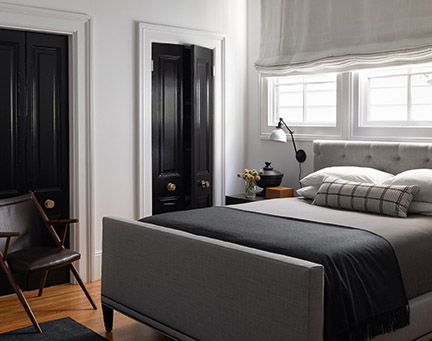Understated and classic bedroom with glossy black closet doors in a room with design by Brian Paquette.