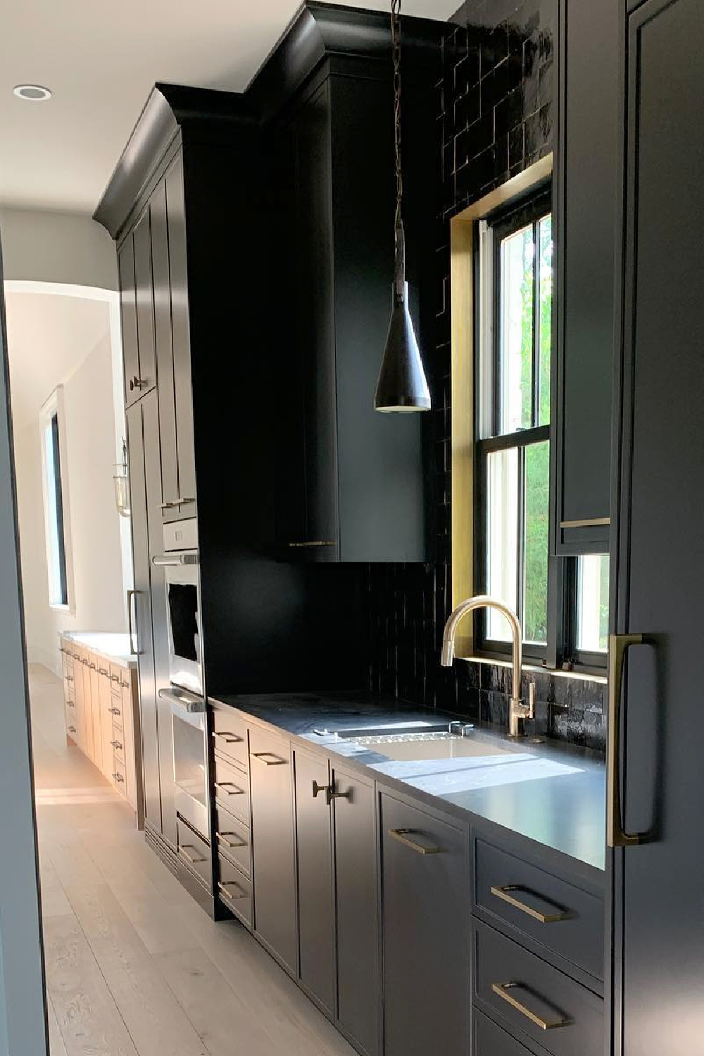 Sherwin-Williams Tricorn Black in a kitchen butler pantry - Ladisic Fine Homes & Matthew Quinn. #tricornblack #blackpaintcolors #blackkitchens #sherwinwilliams