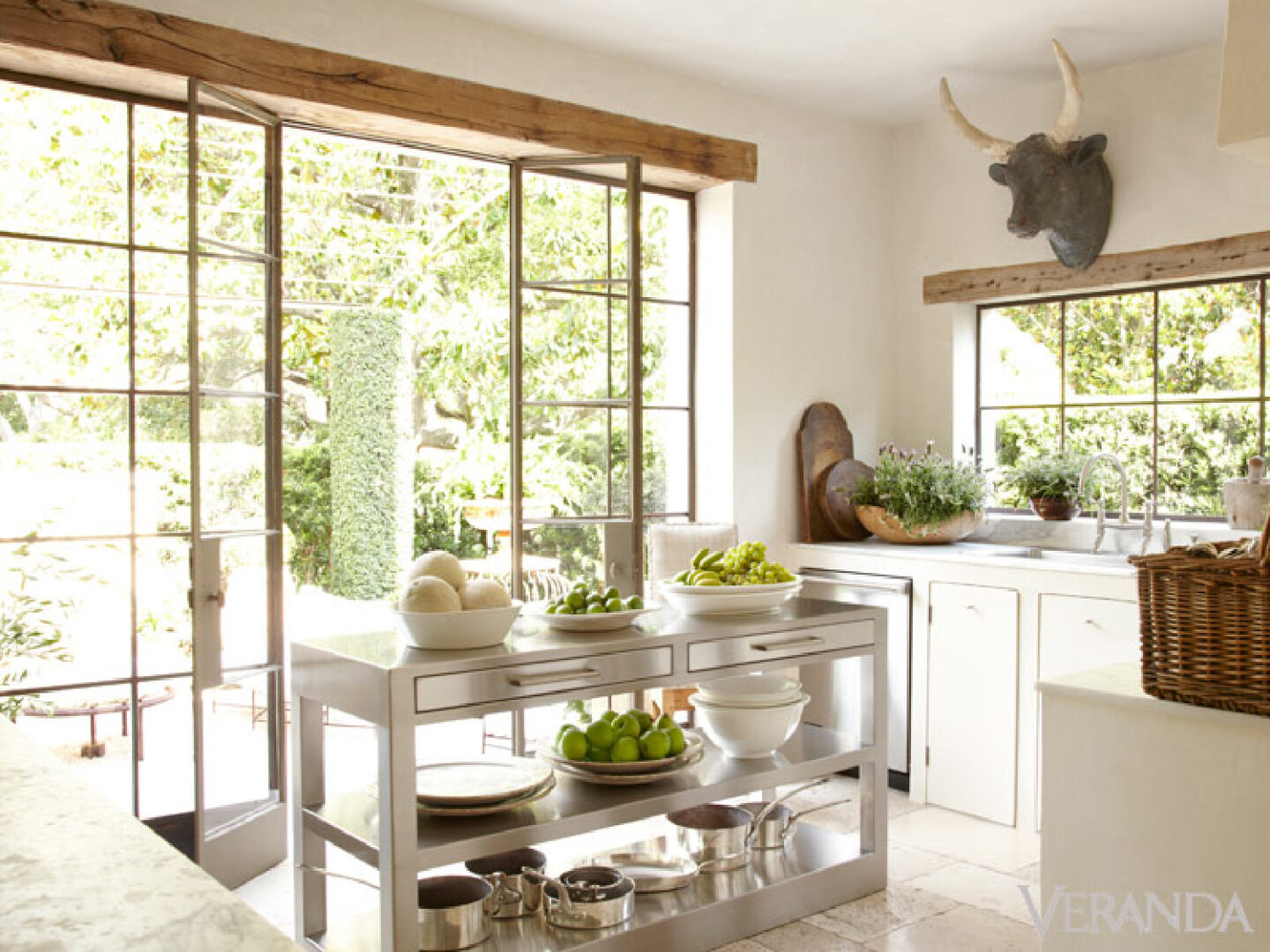 Stunning French Country kitchen with white cabinetry, bull head, steel doors, stainless work island, and design by Pamela Pierce.