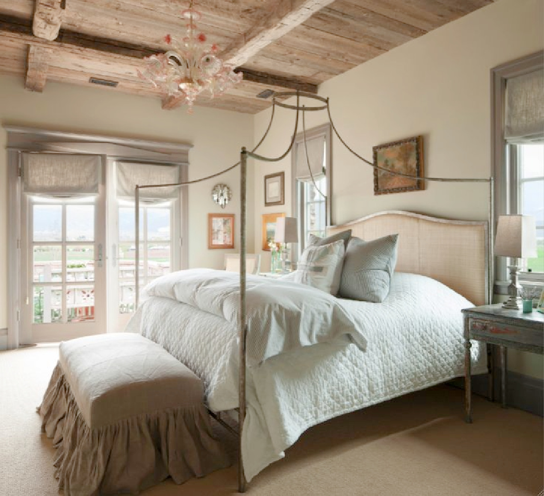 French Gustavian style bedroom with poster bed, rustic wood Old World ceilings, and blue grey stained window trim - Desiree Ashworth of Decor de Provence & Beljar Home.