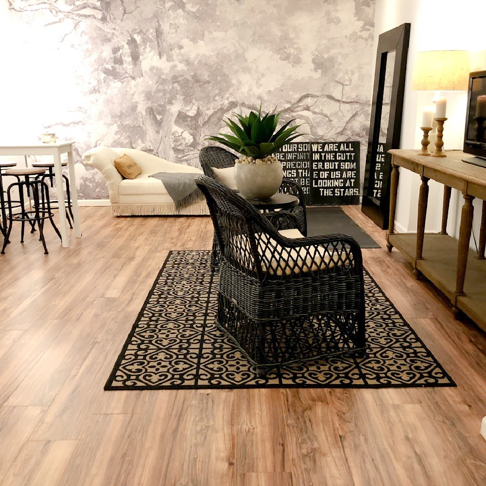 Neutral laminate floors, a mix of woven textures, and a sophisticated mural (Photowall) customized this finished basement space - Hello Lovely Studio. #wallpaper #mural #trees