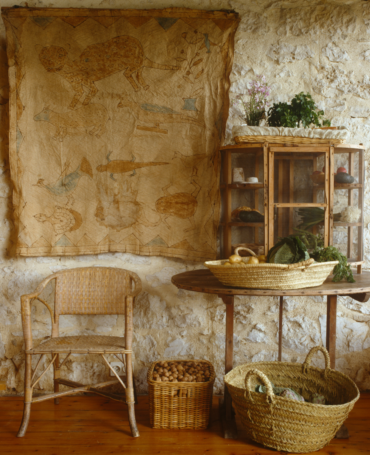 A primitive bark painting from Bali hangs beside an English larder sitting on a 'vigneronne', a collapsible table used by the grape pickers for lunch during the harvest. French provincial inspo in Shauna Varvel's PROVENCE STYLE. #interiordesign #frenchcountry #oldworldstyle