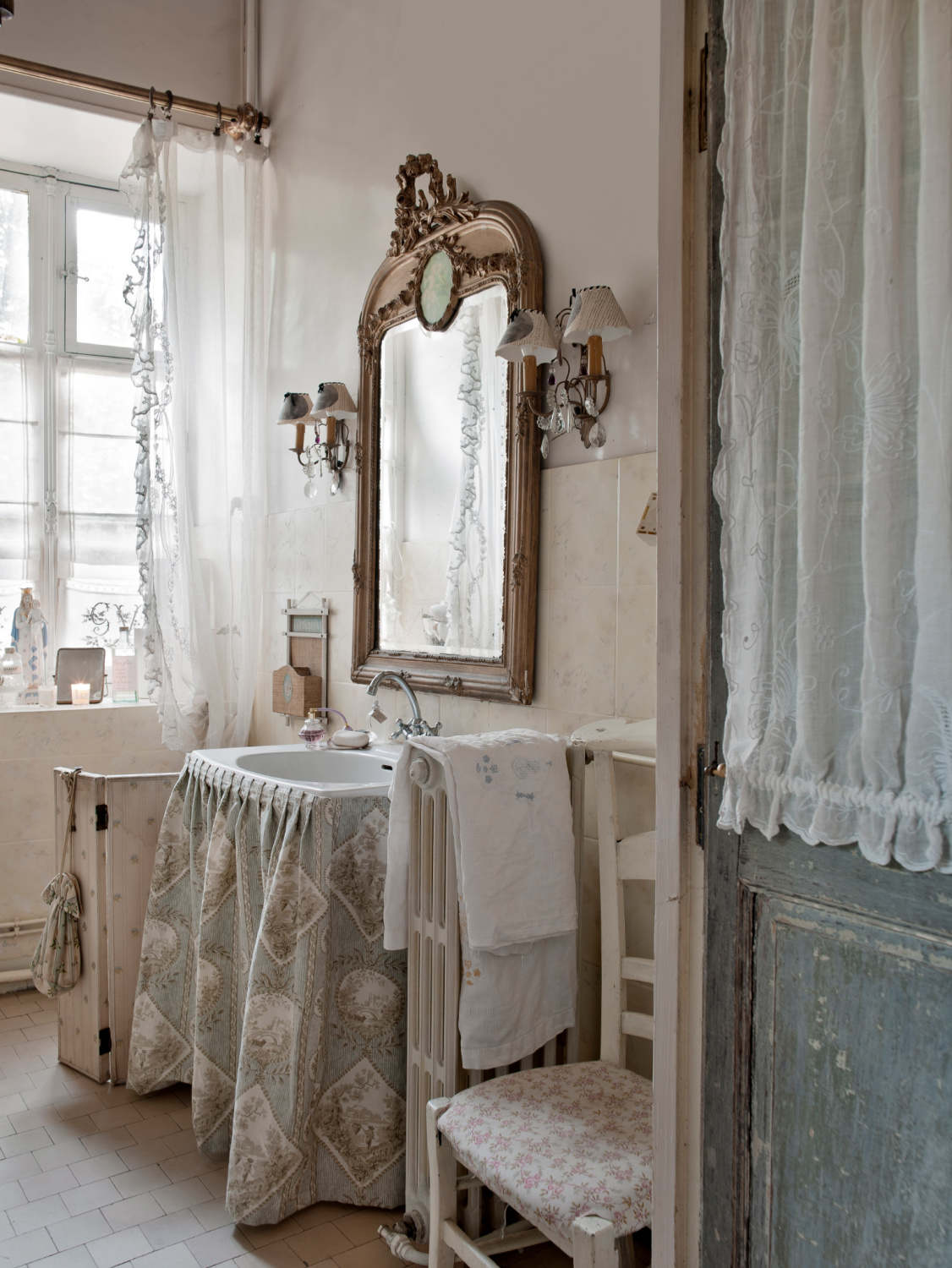 Elegant and traditional bathroom in Provence with ornate mirror, skirted sink, and a pale palette. French provincial style in Shauna Varvel's PROVENCE STYLE. #interiordesign #frenchcountry #oldworldstyle