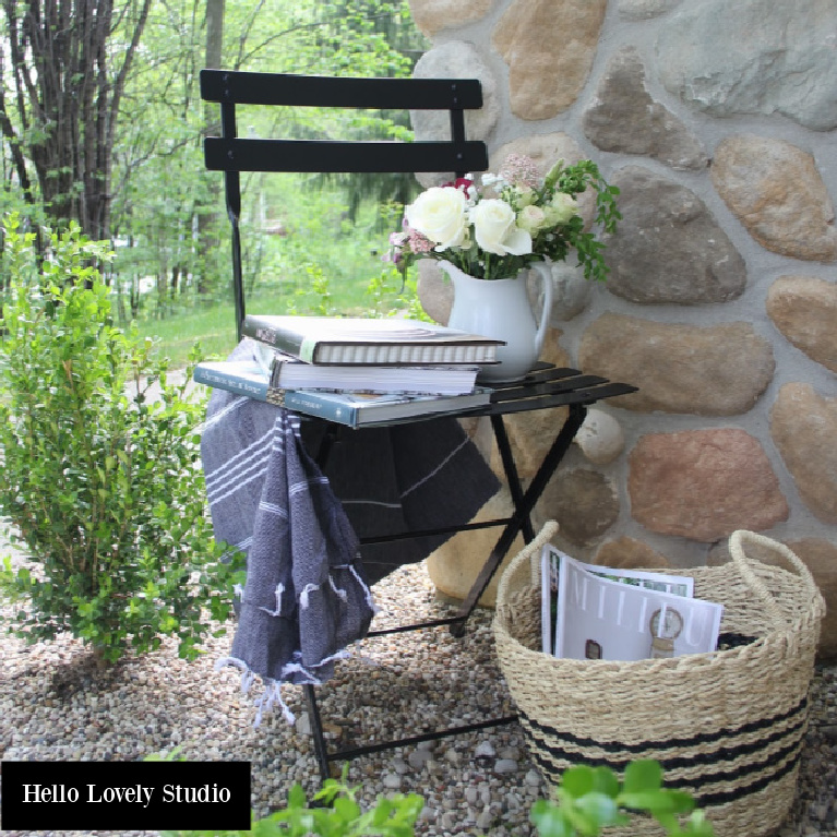 Black Fermob bistro chair, stripe Turkish towel, and seagrass basket for a charming outdoor French farmhouse vignette - Hello Lovely Studio.