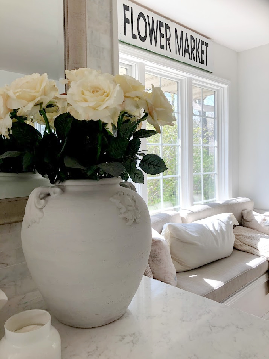 White roses in an antique white urn on my counter in the kitchen with window seat - Hello Lovely. #serenedecor #whiteroses #modernFrench