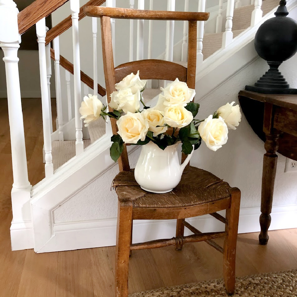 White roses in ironstone pitcher on French prayer chair - Hello Lovely.