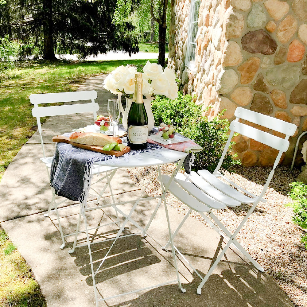 Charmingly French country and rustic casual dining outdoors with white cafe chairs - Hello Lovely Studio. #outdoordining #frenchaesthetic #countryfrench