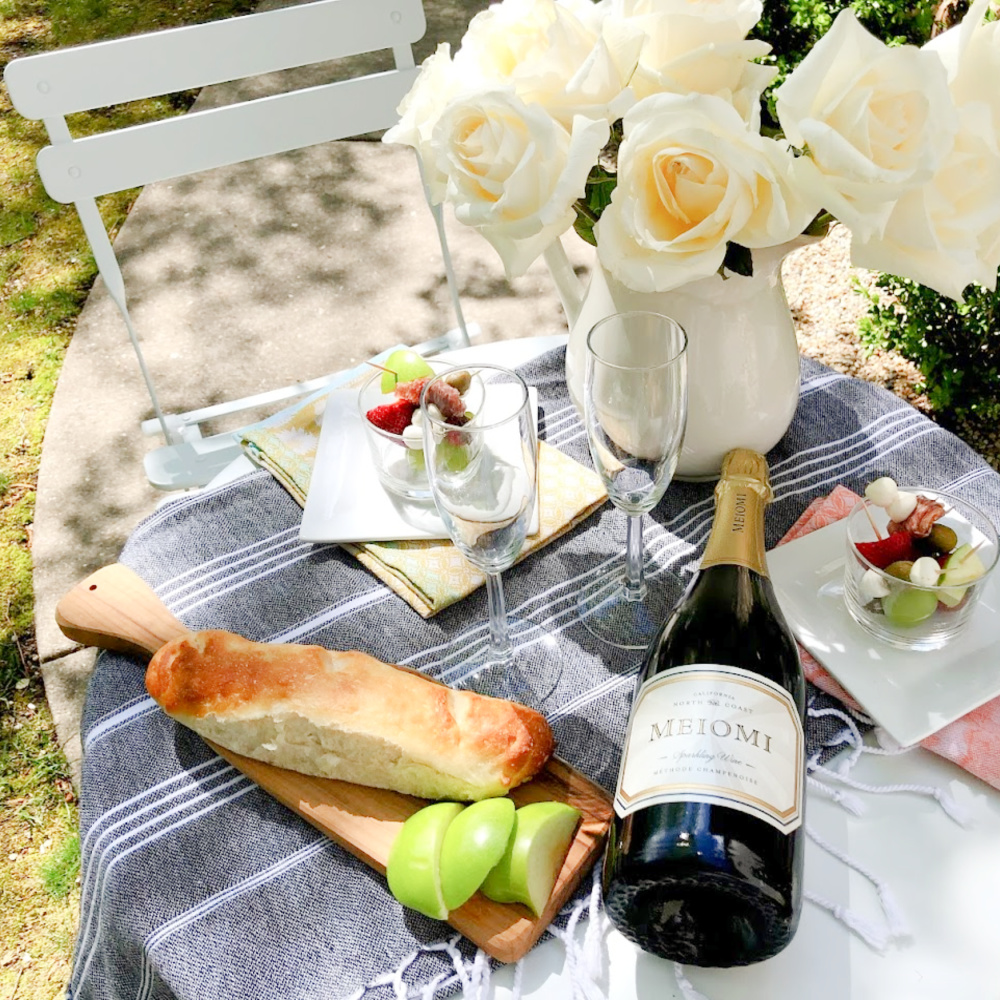 Champagne, jarcuterie and baguette on a charming French cafe dining table in garden - Hello Lovely Studio. #jarcuterie #frenchpicnic #frenchaesthetic #outdoordining