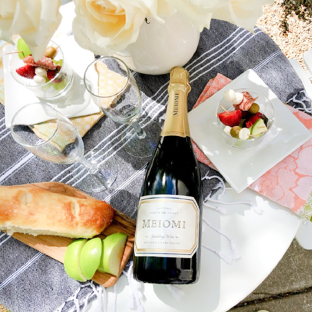 Champagne, jarcuterie and baguette on a charming French cafe dining table in garden - Hello Lovely Studio. #jarcuterie #frenchpicnic #frenchaesthetic #outdoordining