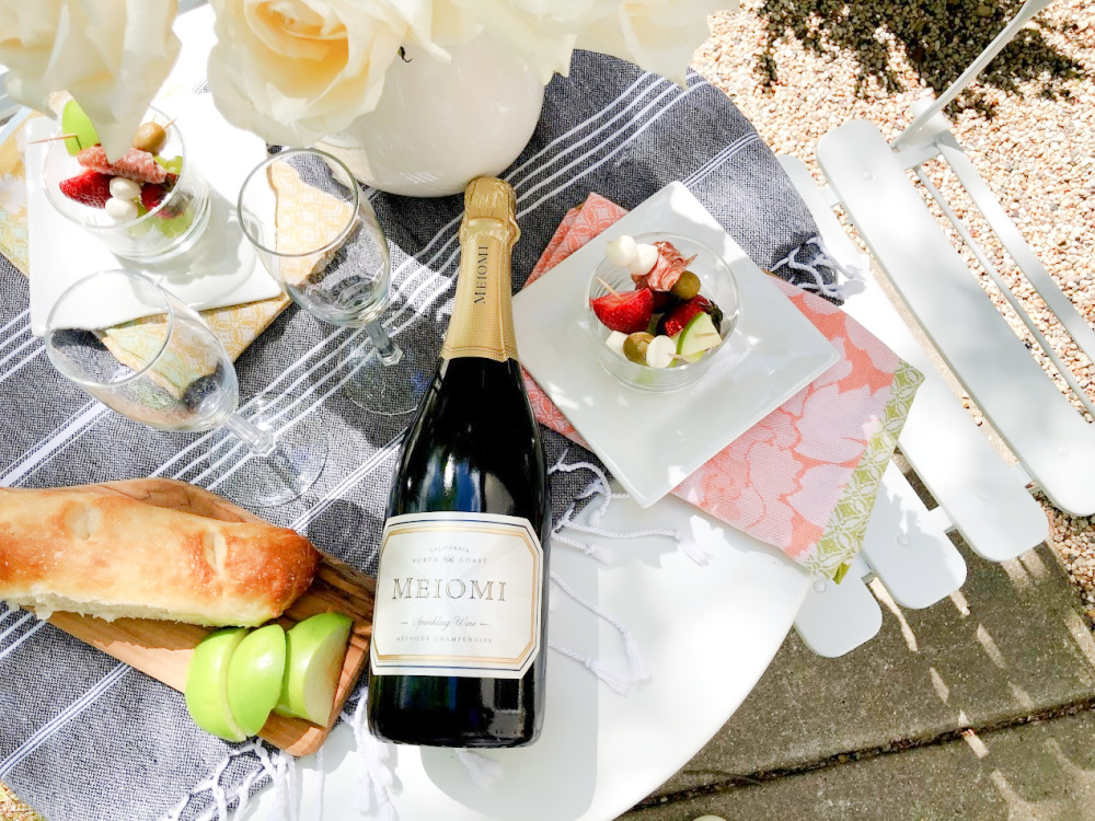 Champagne, jarcuterie and baguette on a charming French cafe dining table in garden - Hello Lovely Studio. #jarcuterie #frenchpicnic #frenchaesthetic #outdoordining