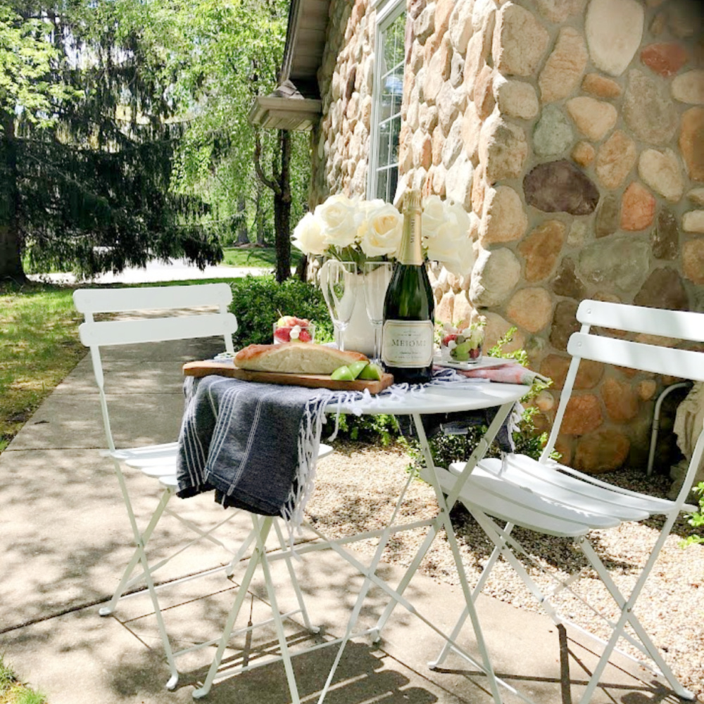 Rustic French country cafe dining in the garden with white roses on the table - Hello Lovely Studio. #frenchcafe #frenchcountry #bistroset #cafeset